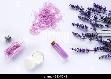 Lavendelblüte, Meersalz, Cremedose und ätherisches Öl auf weißem Hintergrund, Draufsicht, flach liegend. Stockfoto