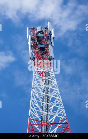 Oberseite eines metallischen rot-weißen selbst unterstützenden zellularen Netzwerk Antennenturm mit mehreren Antennen gegen blauen Himmel, Finnland Stockfoto