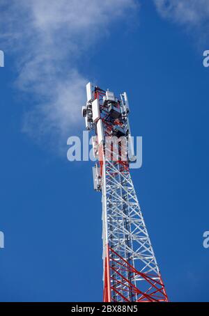 Oberseite eines metallischen rot-weißen selbst unterstützenden zellularen Netzwerk Antennenturm mit mehreren Antennen gegen blauen Himmel, Finnland Stockfoto