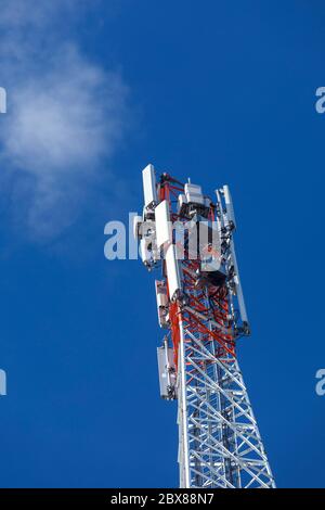 Oberseite eines metallischen rot-weißen selbst unterstützenden zellularen Netzwerk Antennenturm mit mehreren Antennen gegen blauen Himmel, Finnland Stockfoto