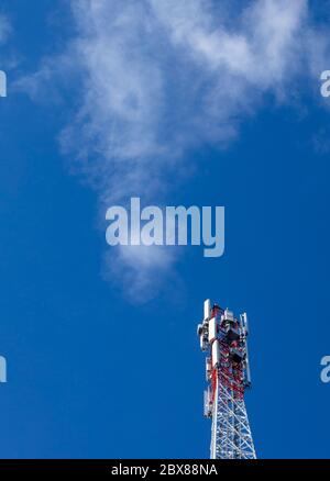 Oberseite eines metallischen rot-weißen selbst unterstützenden zellularen Netzwerk Antennenturm mit mehreren Antennen gegen blauen Himmel, Finnland Stockfoto