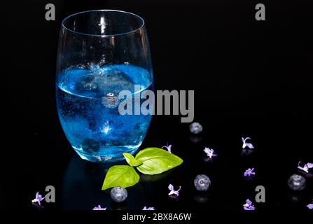 Ein einziges Glas Gin Tonic, mit einem Blaubeer-Tonic und frischen Blaubeeren zum Garnieren Stockfoto