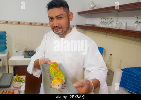 Lifestyle-Porträt von asiatischen Hauskoch Mann oder professionellen Koch Kochen in sauberer Küche zeigt traditionelle japanische Sushi-Roll-Gericht glücklich und stolz ich Stockfoto