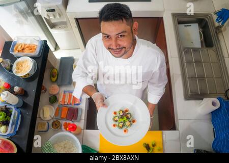 Lifestyle-Porträt von asiatischen Hauskoch Mann oder professionellen Koch Kochen in sauberer Küche zeigt traditionelle japanische Sushi-Roll-Gericht glücklich und stolz ich Stockfoto