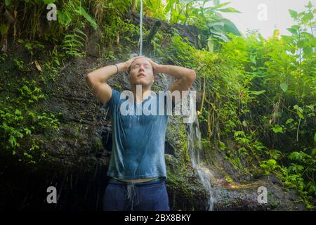 Urlaub Abenteuer Lifestyle Portrait - junger cooler und glücklicher Mann unter natürlichen Dusche aus Wasserfall im Dschungel genießen die Natur unbeschwert und f Stockfoto