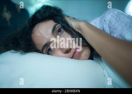 Dramatische Nacht Lebensstil potrait der jungen traurig und deprimiert mittleren östlichen Frau mit lockigen Haaren schlaflos im Bett wach Gefühl besorgt Leiden depr Stockfoto