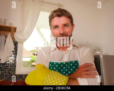 Häusliche Hausarbeit Lifestyle Porträt von 30er bis 40er glücklich und attraktiv Mann trägt Küchenschürze posiert cool genießen Kochen, Waschen und tun Haus Stockfoto