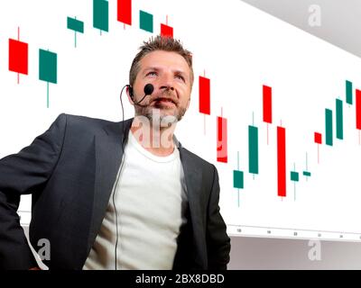 Attraktiver und selbstbewusster erfolgreicher Trader Mann mit Headset spricht bei Webinar Event Coaching Trading Business im Auditorium oder Konferenzraum lehren Stockfoto