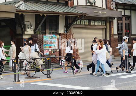 Menschen, die die Straße vor dem alten und jetzt geschlossenen Harajuku Station überqueren. Während des Coronavirus-Ausbruchs tragen Menschen Gesichtsmasken. Stockfoto