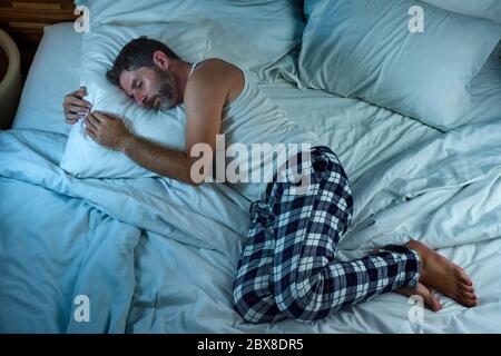 Häusliche Lifestyle Hochwinkel Porträt von jungen attraktiven und entspannten Mann allein auf dem Bett zu Hause liegen ruhig in der Nacht in dunkles Licht ruhen Stockfoto