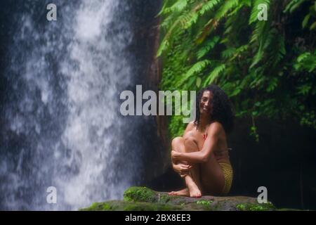 Im Freien tropischen Lifestyle Porträt von jungen attraktiven und glücklich Hipster Mädchen genießen Natur aufgeregt Gefühl frei bei erstaunlich schönen Wasserfall in Stockfoto