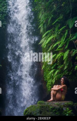 Im Freien tropischen Lifestyle Porträt von jungen attraktiven und glücklich Hipster Mädchen genießen Natur aufgeregt Gefühl frei bei erstaunlich schönen Wasserfall in Stockfoto