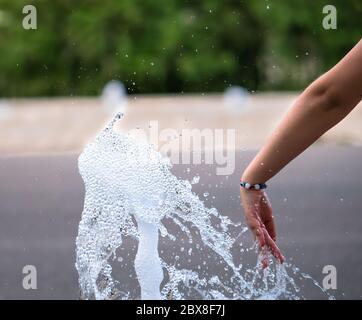 Mädchen Hand spielt mit einem Strom von Wasser aus einem Brunnen Stockfoto