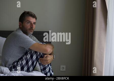 Dramatische Porträt von attraktiven Angst und depressive 40er Mann auf dem Bett im Pyjama Gefühl besorgt Leiden Angst und Depression Problem während Virus q Stockfoto
