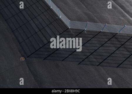 Luftaufnahme eines Zauns auf Asphalt und Schatten. Stockfoto