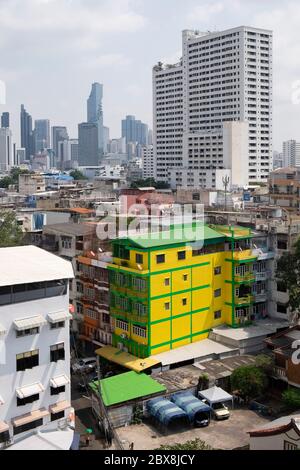 Gelb-grünes Gebäude und im Hintergrund die Skyline des Silom-Gebiets im Hintergrund. Bangkok, Thailand, Südostasien. Stockfoto