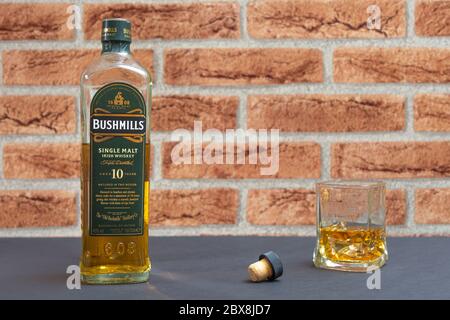 Eine Flasche Bushmills Single Malt Whiskey mit einem Glas vor einem Klinker Hintergrund Stockfoto