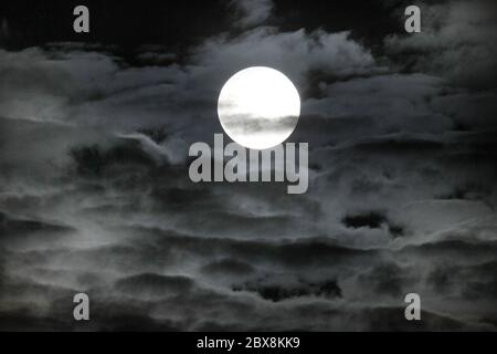 Penumbare Mondfinsternis am 5. Juni 2020 in Deutschland. Heller Vollmond, der durch dunkle Nachtwolken scheint. Mystischer Hintergrund für Bücher und Wissenschaft. Stockfoto