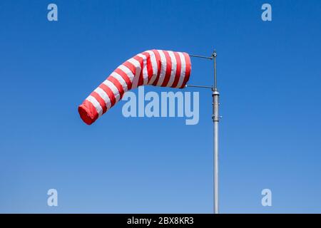 Windsock-Flagge, Windgeschwindigkeitsmesser, rote und weiße Streifen auf blauem Hintergrund Stockfoto
