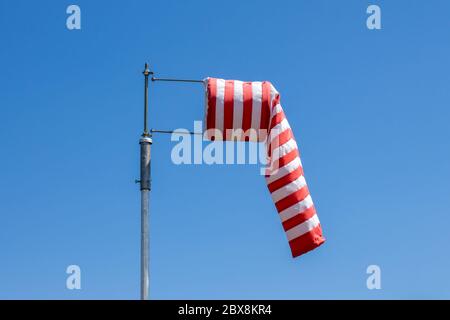 Windsock-Flagge, zeigt keinen Wind, rote und weiße Streifen auf blauem Hintergrund Stockfoto