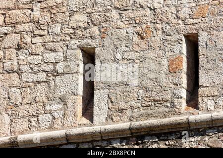 Nahaufnahme einer mittelalterlichen Burgmauer mit zwei Pfeilschächten oder Schlupflöchern. Castello del Buonconsiglio oder Castelvecchio in der Stadt Trient. Trentino-Südtirol.
