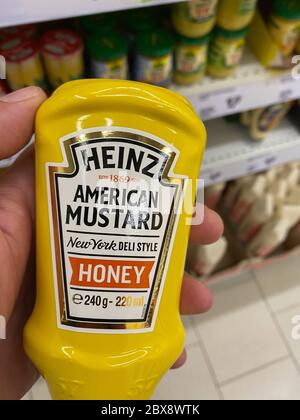 Tönisvorst, Deutschland - 5. Juni. 2020: Nahaufnahme der Hand, die im deutschen Supermarkt eine Flasche Heinz amerikanischen Honigsenf vor dem Regal hält Stockfoto