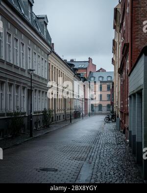 Eine leere Kopfsteinpflasterstraße, die an einem regnerischen Tag in Malmö, Schweden, mit alten bunten Häusern umsäumt ist Stockfoto