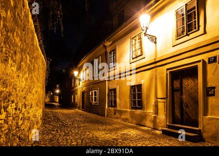 Schmale gepflasterte Straße in alten mittelalterlichen Stadt mit beleuchteten Häusern von Vintage-Straßenlampen, Novy svet, Prag, Tschechische Republik. Nachtaufnahme. Stockfoto