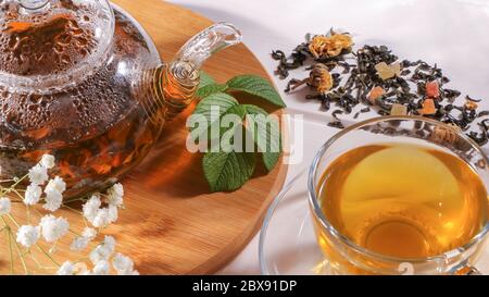 Eine Tasse grüner Tee und eine Teekanne. Blumentee mit Obstscheiben. Teezeremonie, traditionelles Getränk. Nachmittagstee, heimelig. Flaches Lay. Orientalisch, gemütlich, vorher Stockfoto