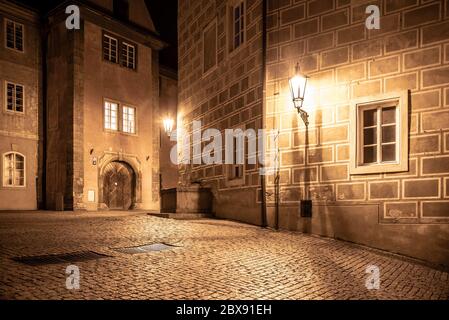 Mittelalterliche Häuser und alte Trinkbrunnen in Golden Lane bei Nacht, Prager Burg, Tschechische Republik. Stockfoto