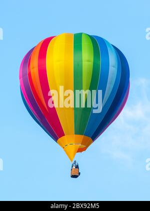 Heißluftballon in Regenbogenfarben auf blauem Himmel Hintergrund. Stockfoto