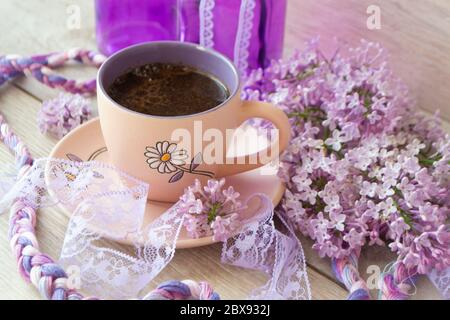 Violette Tasse Kaffee oder Cappuccino und zarte lila, lila Blüten. Muttertag Konzept. Gemütliches Frühstück Stockfoto