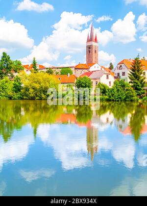 Turm der Kirche des Heiligen Geistes in Telc an sonnigen Sommertag im Wasser reflektiert, Tschechische Republik. Stockfoto