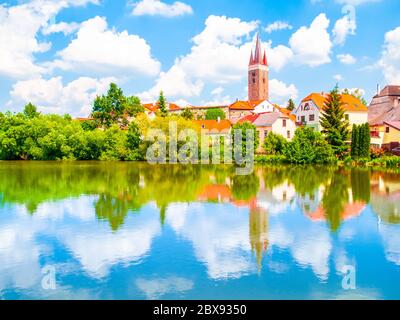 Turm der Kirche des Heiligen Geistes in Telc an sonnigen Sommertag im Wasser reflektiert, Tschechische Republik. UNESCO-Weltkulturerbe. Stockfoto