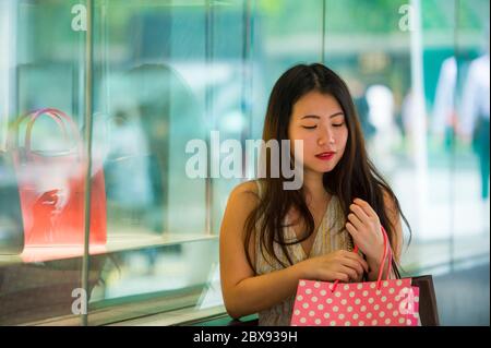 Junge schöne und elegante asiatische koreanische glückliche Frau mit Einkaufstaschen zu Fuß auf der Straße neben Kleidung Schaufenster nach dem Kauf Schönheit Zeug Stockfoto