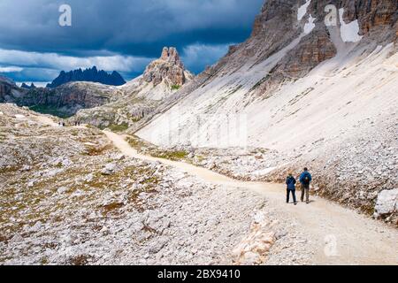 Bergwanderer mit Wanderstöcken wandern auf dem felsigen Weg in den Bergen. Nordic Walking-Thema. Stockfoto