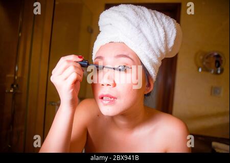 Lifestyle frisch Porträt von jungen glücklich und schöne asiatische chinesische Frau zu Hause oder im Hotel Bad in WC Handtuch Anwendung Make-up fröhlich eingehüllt Stockfoto