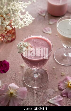 Ein Glas Ziegenkefir mit gemischten Himbeeren und Holunderblüten Stockfoto