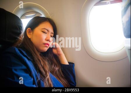 Lifestyle offen Porträt von jungen glücklich und schön asiatisch chinesische Frau, die geschäftlich in Flugzeug Kabine schlafen während langen Flug in Stockfoto