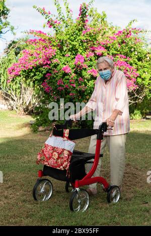 Ältere Dame mit Maske immer Bewegung gehen für einen Spaziergang im Garten Stockfoto