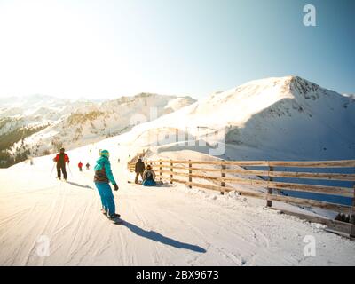 Snowboarder und Skifahrer auf der Piste. Sonniger Wintertag im Skigebiet Saalbach Hinterglemm Leogang, Österreich, Alpen, Europa. Stockfoto