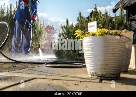 Männer Tragen Nassmantel Reinigung Garten Wege Mit Druckwaschanlage. Heim und Garten Wartung. Stockfoto