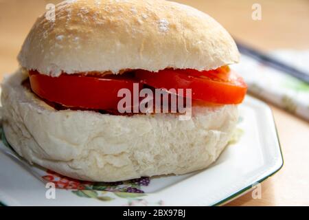 Speck und Tomate auf einem Beilagenteller mit Serviette und Messer zur Seite Rollen Stockfoto