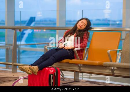 Lifestyle-Porträt von jungen ziemlich müde und erschöpft asiatischen koreanischen touristischen Frau im Flughafen schlafen gelangweilt sitzen am Boarding Gate Halle warten auf Stockfoto