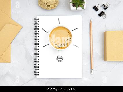 Glühbirne Symbol aus einer frischen Tasse Kaffee und eine Skizze auf einem Spiralnotizbuch. Büro Arbeitsplatz flach legen. Erfrischungs- und Produktivitätskonzept. Bo Stockfoto