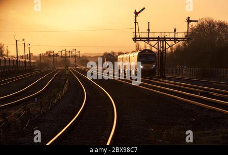 Erster TransPennine Express Siemens Dieselzug der Baureihe 185 185128, der das große Semaphore-Bracket-Signal in Barnetby, Lincs, durchfährt und im Sonnenuntergang glänzen lässt Stockfoto