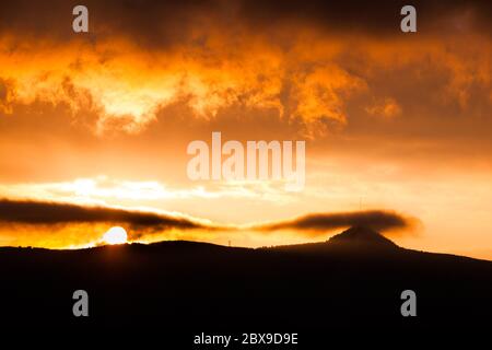 Der Berg Jested versteckt sich in den Wolken. Dramatischer roter Himmel bei Sonnenuntergang. Liberec, Tschechische Republik. Stockfoto