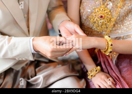 Braut und Bräutigam setzen Ehering auf Finger, Thai Hochzeit Verlobungszeremonie Stockfoto