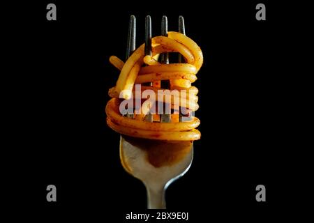 Nahaufnahme der italienischen Spaghetti auf einer Gabel mit Tomatensauce auf schwarzem Hintergrund. Typisch italienisches Essen, Stereotyp, um die italienische Kultur zu identifizieren. Hochwertige Fotos Stockfoto