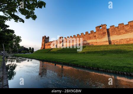 Castelfranco Veneto Stadt, die alten mittelalterlichen Mauern bei Sonnenuntergang (XII-XIII Jahrhundert) mit dem Wassergraben voller Wasser und der Böschung. Treviso, Italien. Stockfoto